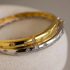 Both the gold and silver North Star Diamond Bangles stacked on top of each other, showing a close up of the North Star design.