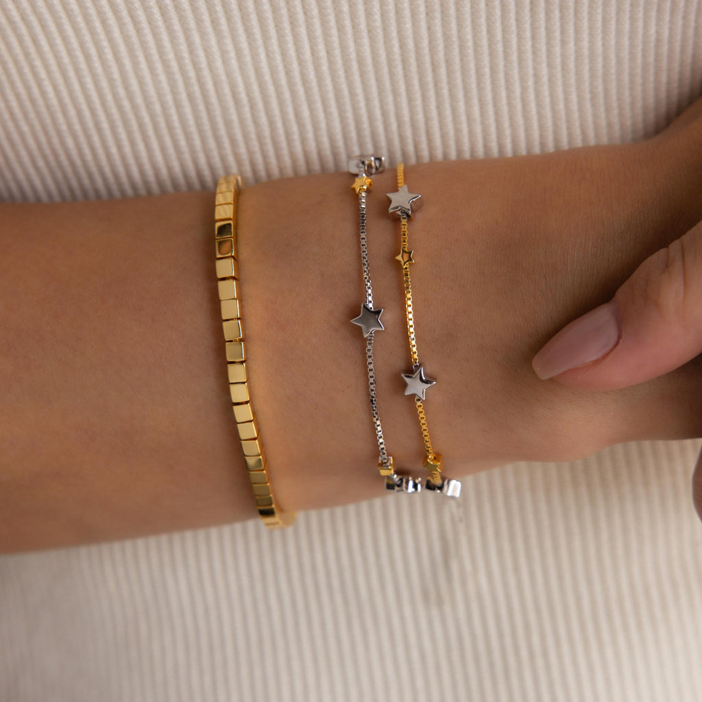 Model wearing Mixed Metal Star Bracelet, layered with a gold cube bracelet.