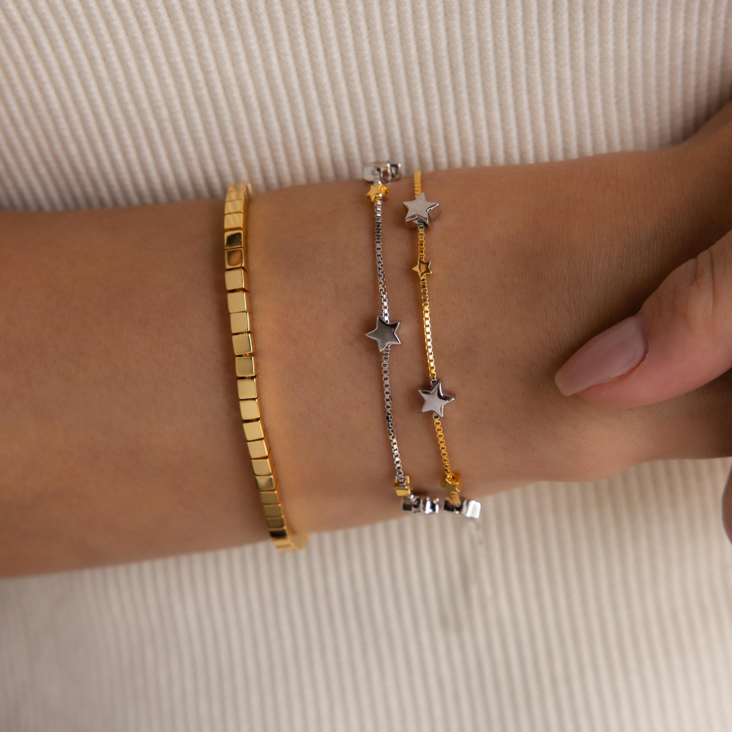 Model wearing Mixed Metal Star Bracelet, layered with a gold cube bracelet.