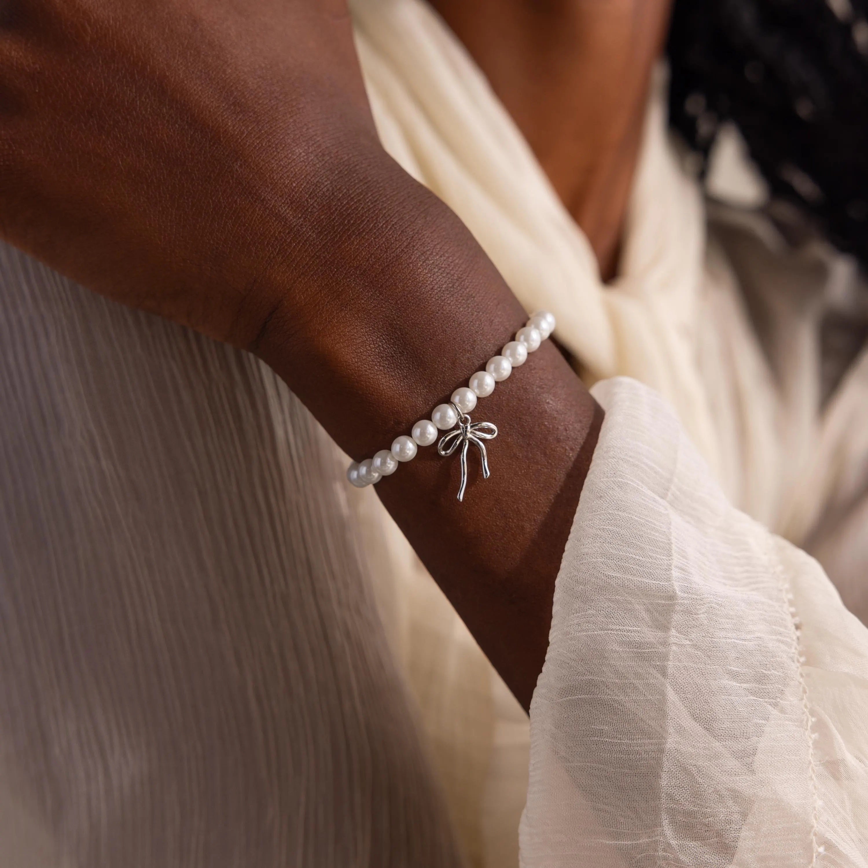 The Bow Pearl Bracelet in white gold is shown on a model's wrist.