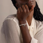 A model rests her chin on her hand, wearing the Bow Pearl Bracelet in white gold.