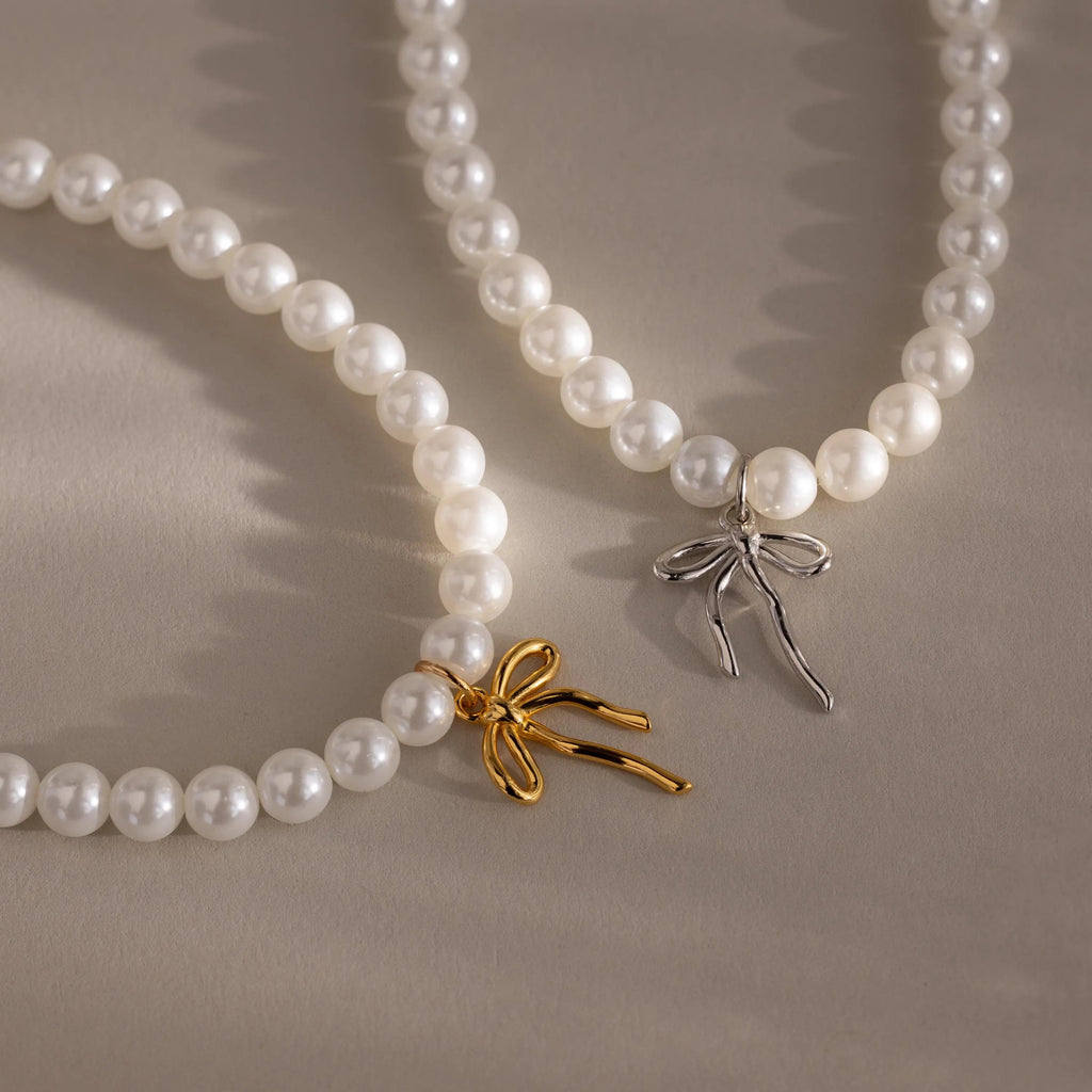 One gold and one silver Bow Pearl Bracelet positioned side-by-side on a neutral background.