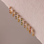 Geometric Birthstone Huggies—gold earrings featuring colorful gemstones in diagonal lines on a soft pink background, highlighted with sparkling diamond accents—are a stunning example of birthstone jewelry.