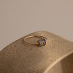 The Multiple Birthstone Bead Ring in Rose Gold features five colorful gemstone bands and sits on a textured beige surface, making it ideal for those who love personalized jewelry.