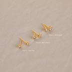 The Booker Diamond Studs Set features three pairs of lightweight gold earrings in small, medium, and large sizes on a light beige background—ideal for everyday wear.