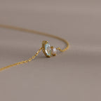 A delicate gold chain bracelet featuring a marquise amethyst and a small pearl, perfect as a gift, set against a soft beige background.