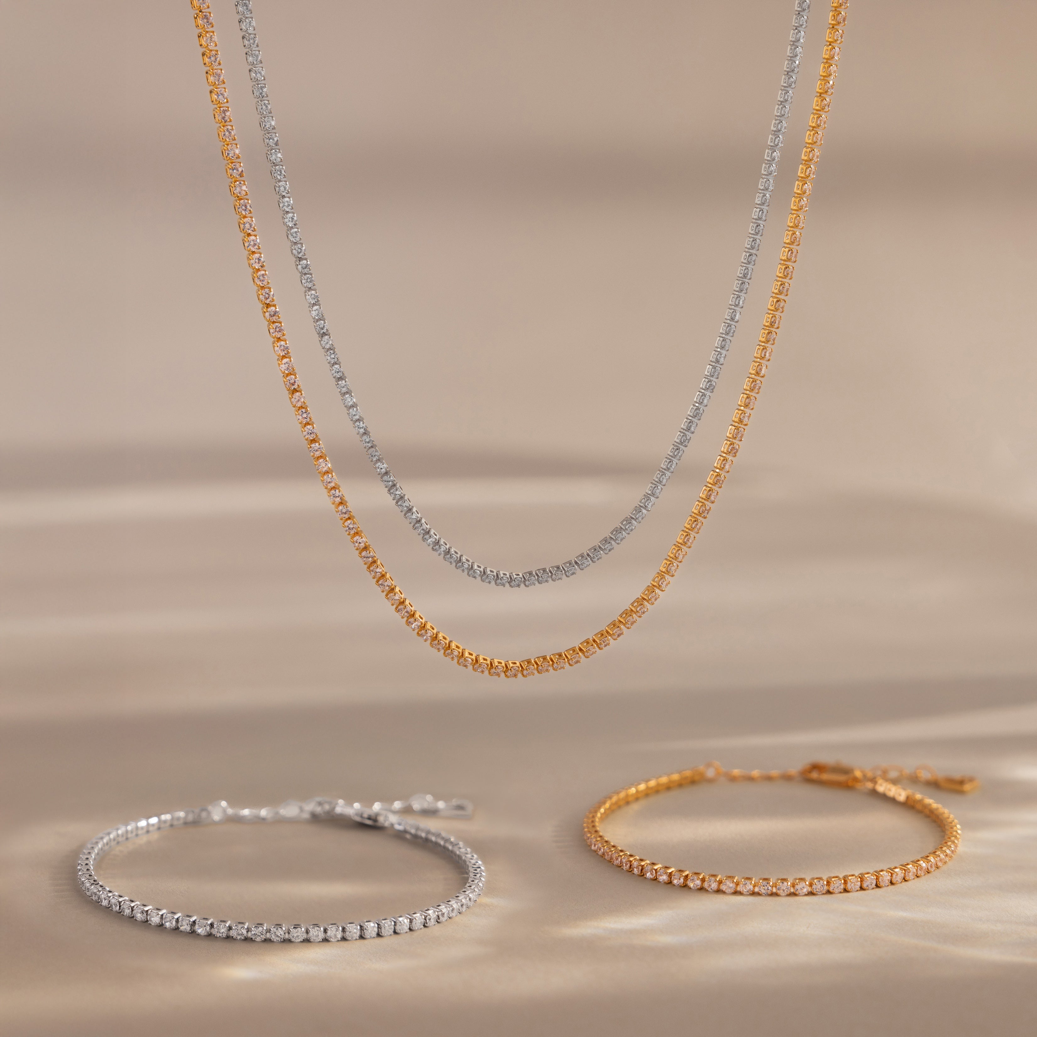 The Dainty Diamond Tennis Necklace & Bracelet Set, shown in both gold and silver on a neutral background, highlights delicate diamond jewelry ideal for elegant looks.