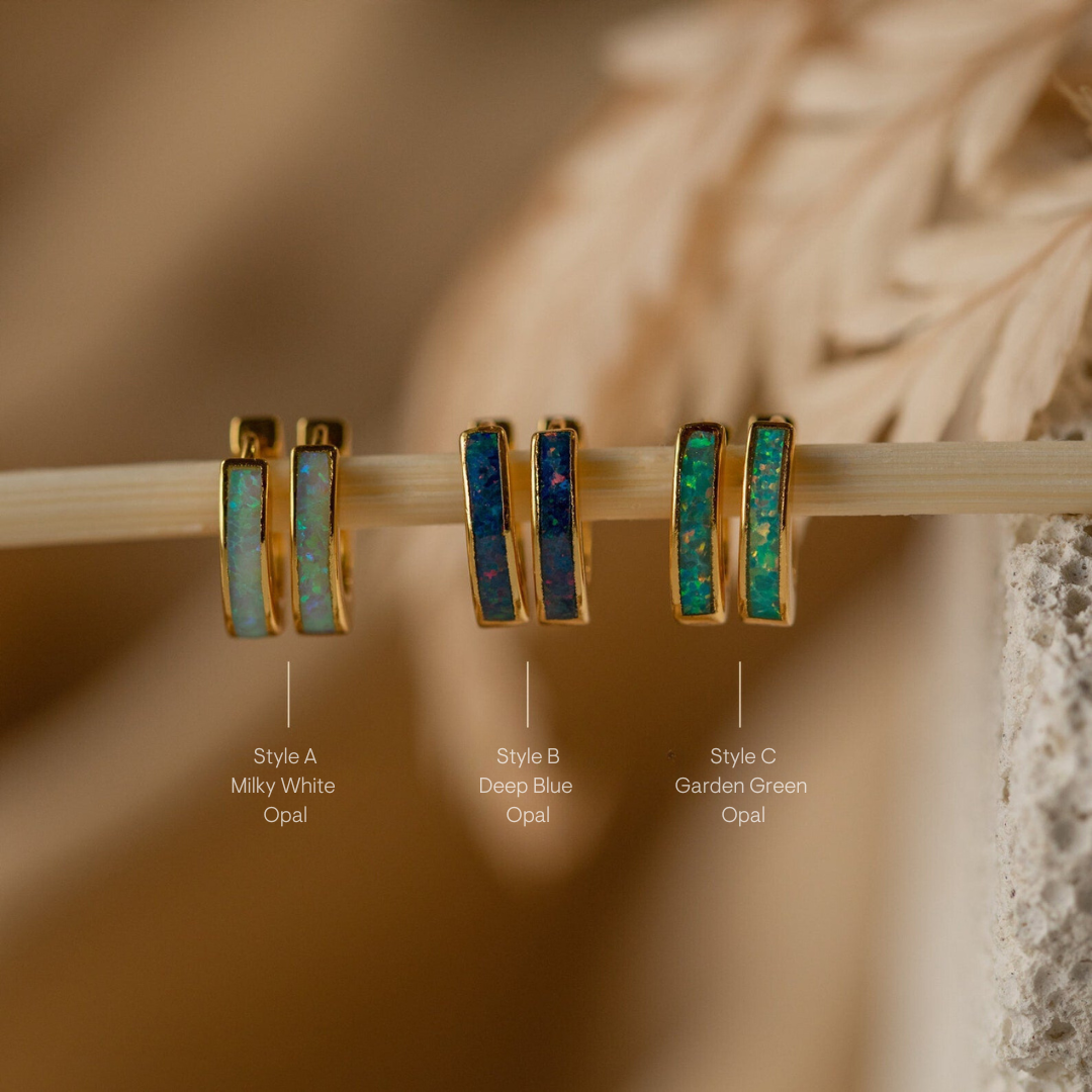The Opal Inlay Huggies Set features a row of hoop earrings, each pair showcasing a unique opal inlay that catches the light and displays stunning colors.