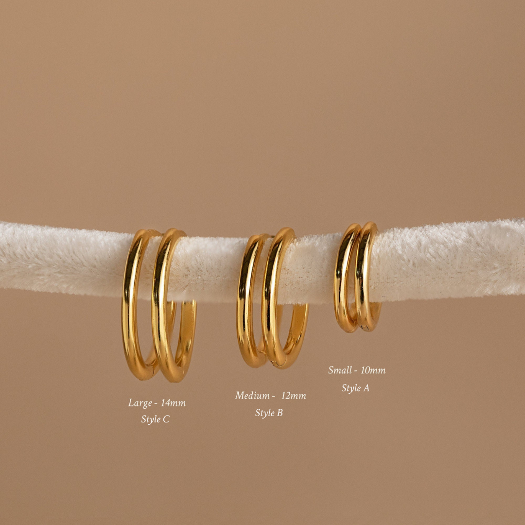 The Mini Bold Hoops Set features three pairs of classic hoop earrings in small, medium, and large sizes on a white textured rod—a striking addition to any Hoop Earrings Collection.