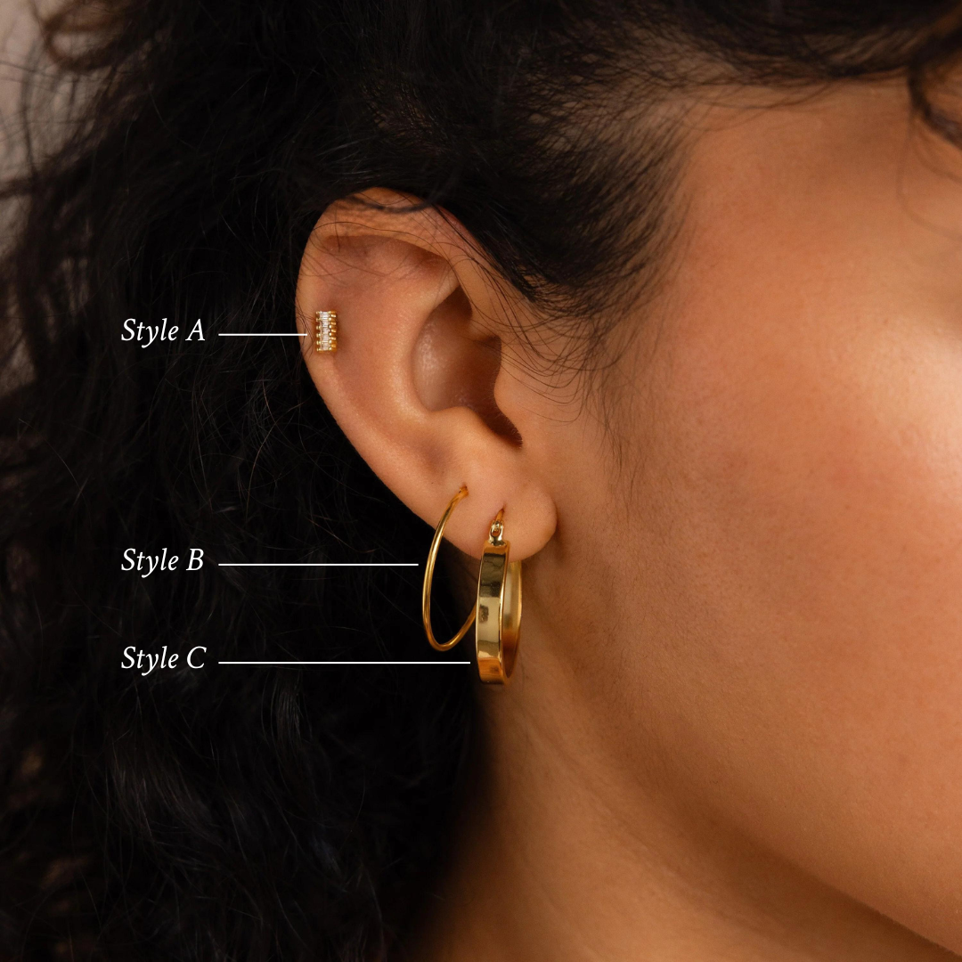 Close-up of an ear wearing the Bold Earrings Stack Set—featuring a stud, thin hoop, and thick hoop—to showcase a chic layered look with gold earrings.