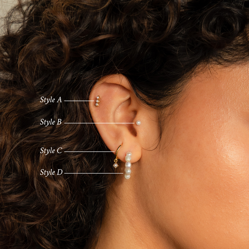 Close-up of a woman’s ear wearing the Pearl Earrings Set, showcasing four styles—including elegant hoops and classic studs—framed by her curly hair.