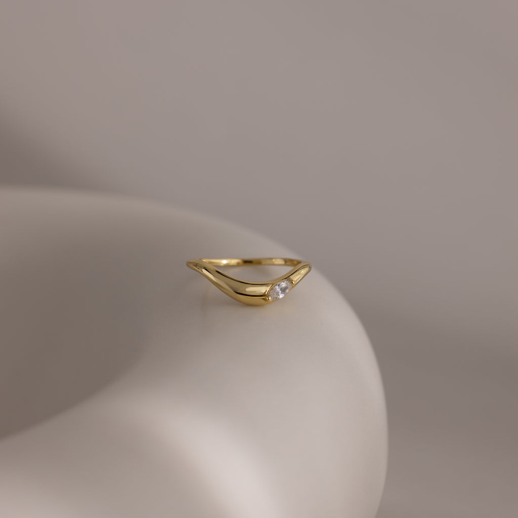 The Zen Gemstone Curve Ring showcases its minimalist style and a delicate gemstone accent, elegantly set on a sleek, neutral band.