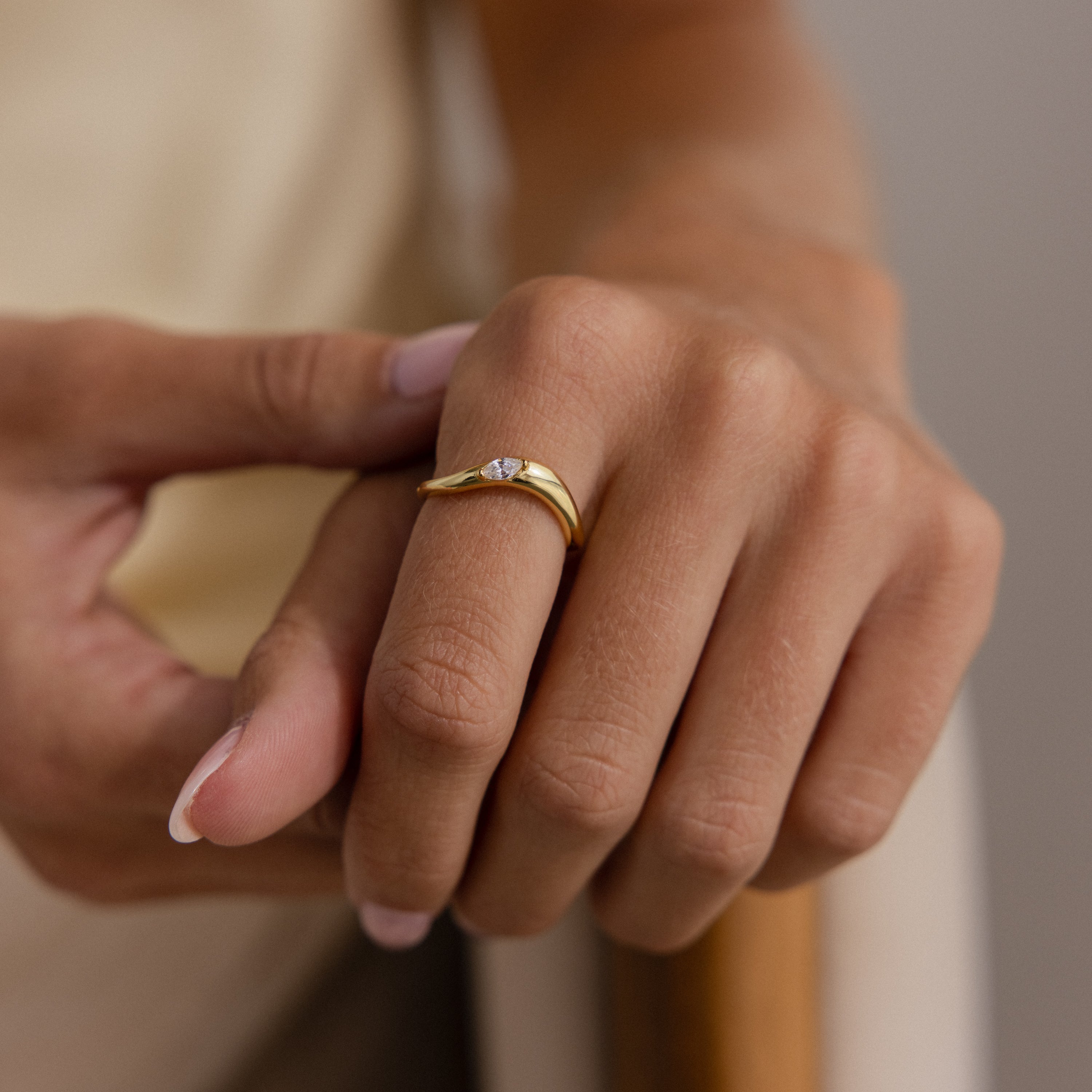 A hand wears the Zen Gemstone Curve Ring, showcasing its minimalist design and delicate gemstone accent, with gently curled fingers and neatly manicured nails.