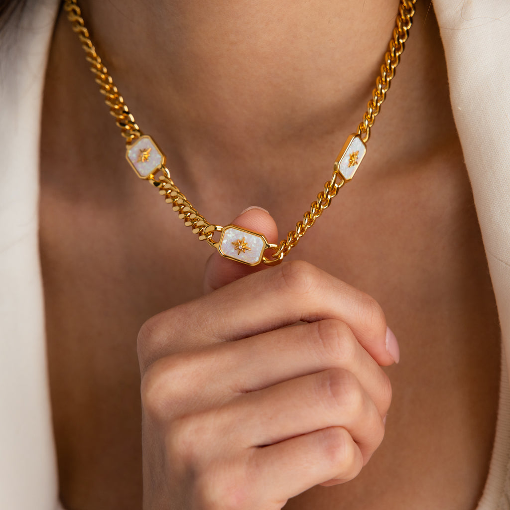 Model showcasing a gold thick curb chain necklace with 3 iridescent opal north star charms.