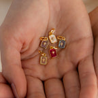 Multiple gold north star birthstone charms in hand.