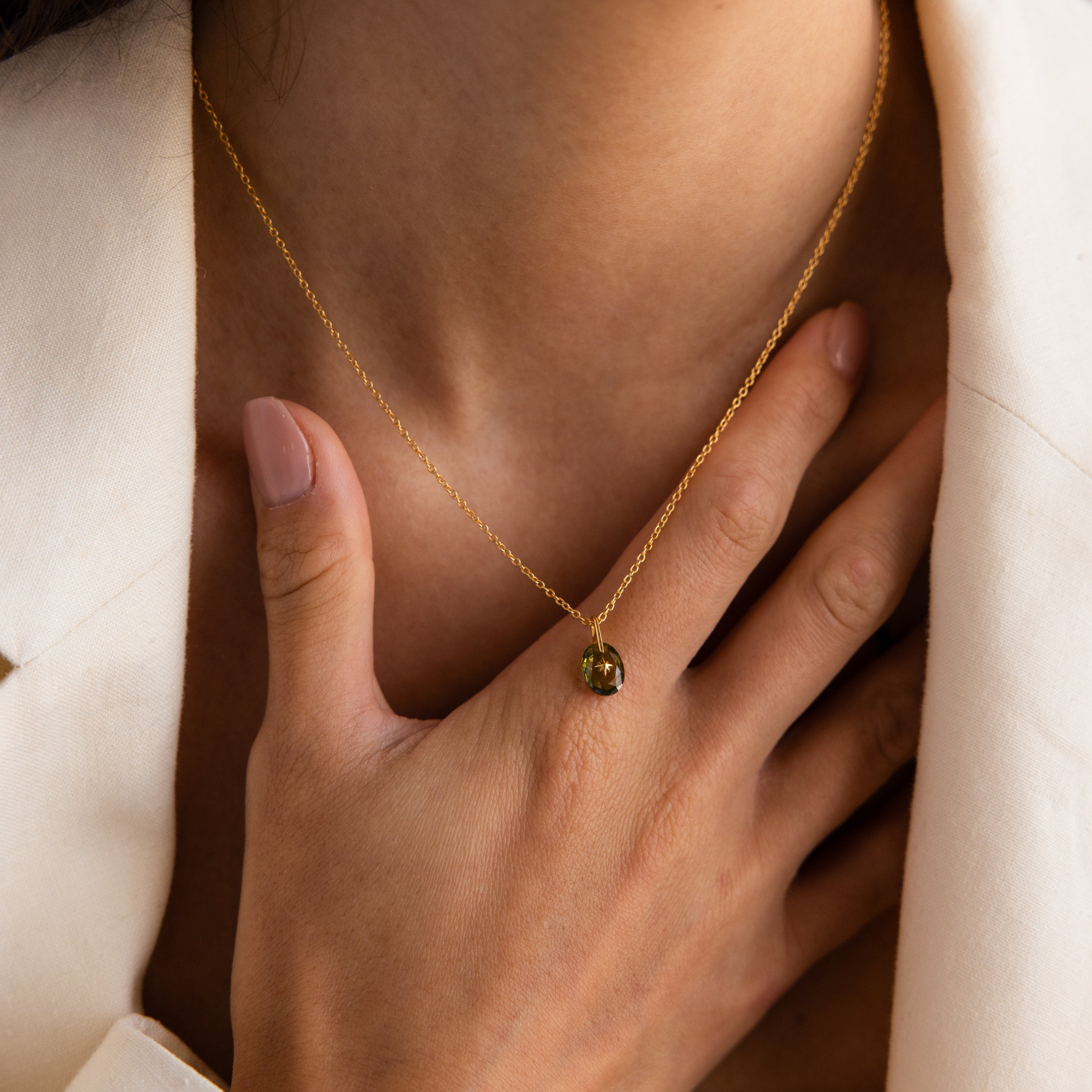 Close-up of model wearing a Gold North Star Birthstone Necklace with a Green Peridot Gemstone.