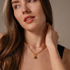 Woman with long brown hair wears a black top and gold chain necklaces, featuring the Onyx Honeybee Charm in Silver.