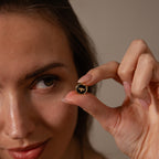 A woman holds the Onyx Honeybee Charm in 18K Gold, a small round pin featuring a gold bee design—please provide the actual product description to identify important SEO keywords.