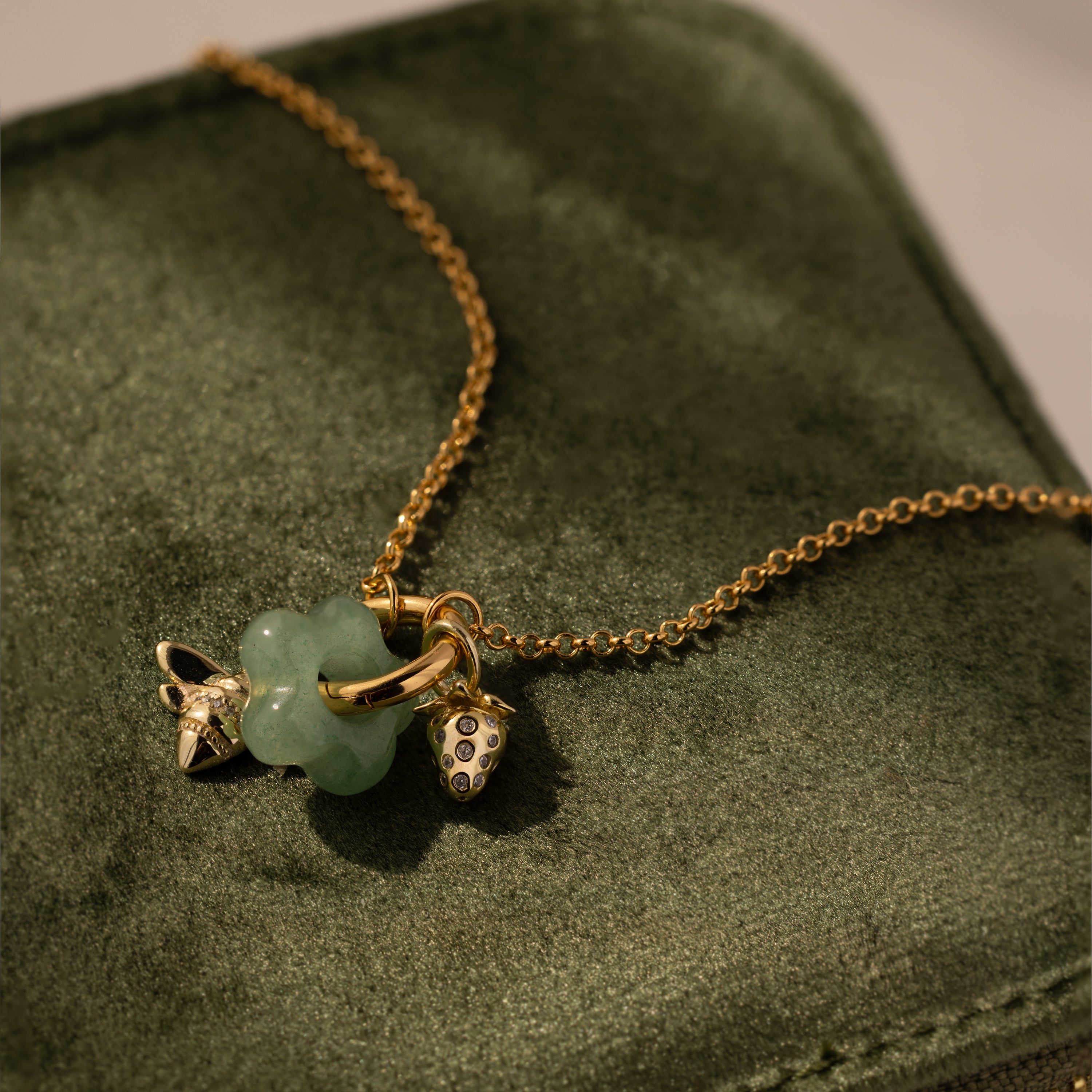 Jade Flower Charm gold chain necklace features a green clover charm and small gold pendants, elegantly displayed in a green velvet box—an exquisite jewelry gift for any occasion.