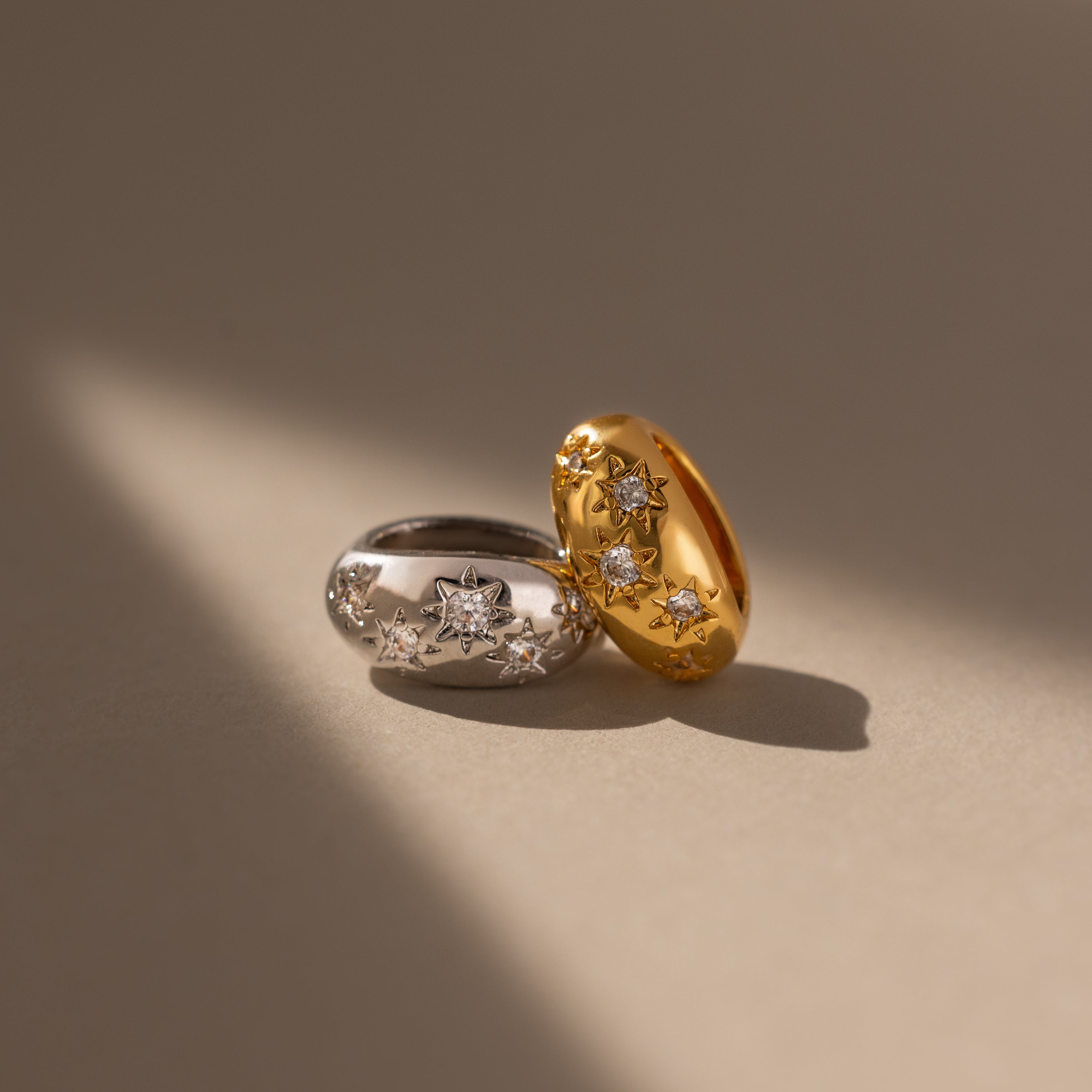 The Sprinkle Diamond Dome Charm shines on a neutral background with soft lighting, featuring starburst-set stones and star-shaped diamond accents in gold and silver.