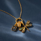 18K gold necklace featuring the Sprinkle Diamond Dome Charm, paired with a starburst stones pendant, an oval with diamonds, and a dragonfly charm on blue.
