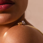 Close-up of a woman's shoulder with two Sprinkle Diamond Dome Charms—one styled with a starburst set stones design—balanced on it, her lips softly visible in the frame.