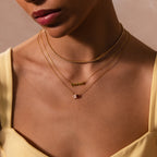 Woman wearing a yellow top showcases effortless necklace stacking with the Triple Layering Clasp, highlighting three layered gold necklaces around her neck and collarbone.