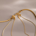 Four gold necklaces with different chain styles are displayed on a neutral background, highlighting the Triple Layering Clasp for easy necklace stacking and tangle-free wear.
