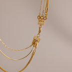 Close-up of layered gold necklaces with various chain styles, highlighted by the Triple Layering Clasp in 18K Gold for easy necklace layering, set against a neutral background.
