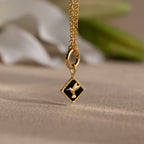 The Onyx Hummingbird Charm in 18K Gold features a delicate bird design on a black background. This elegant necklace is a unique statement piece, perfect for elevating any outfit and enhancing your jewelry collection.