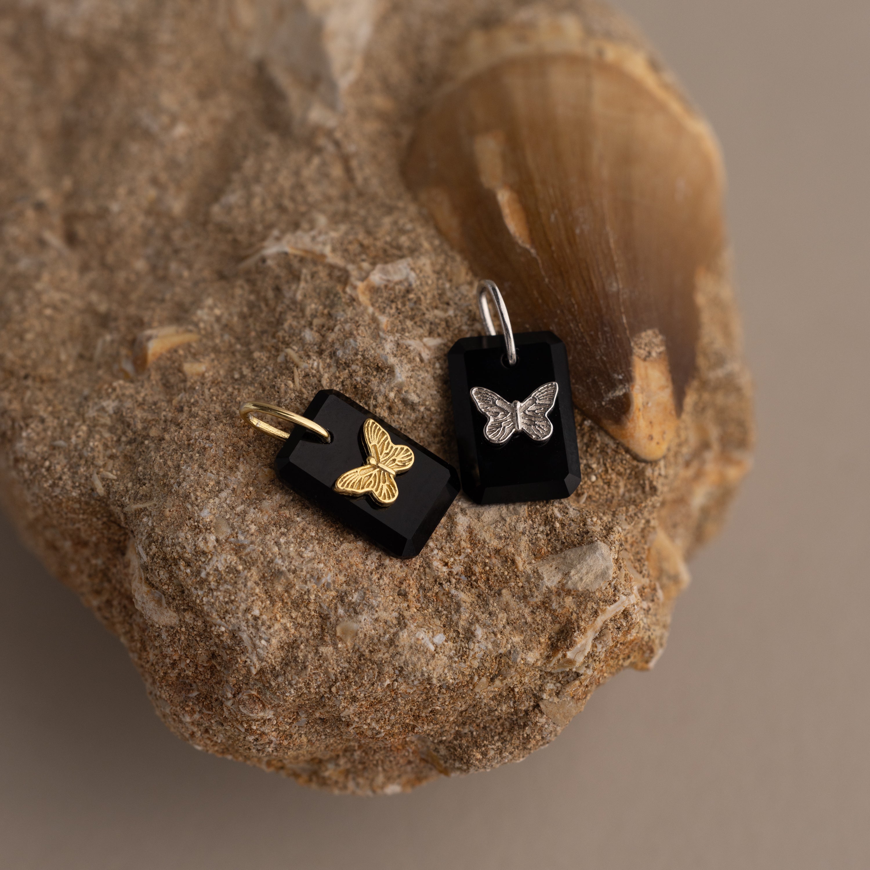 The Onyx Butterfly Charm in Silver features a delicate butterfly design on a sleek black rectangular pendant, combining nature-inspired elegance with modern style.