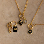 Three gold necklaces feature various charms such as letters, butterflies, birds, and a teardrop-shaped gem—including the Onyx Hummingbird Charm.