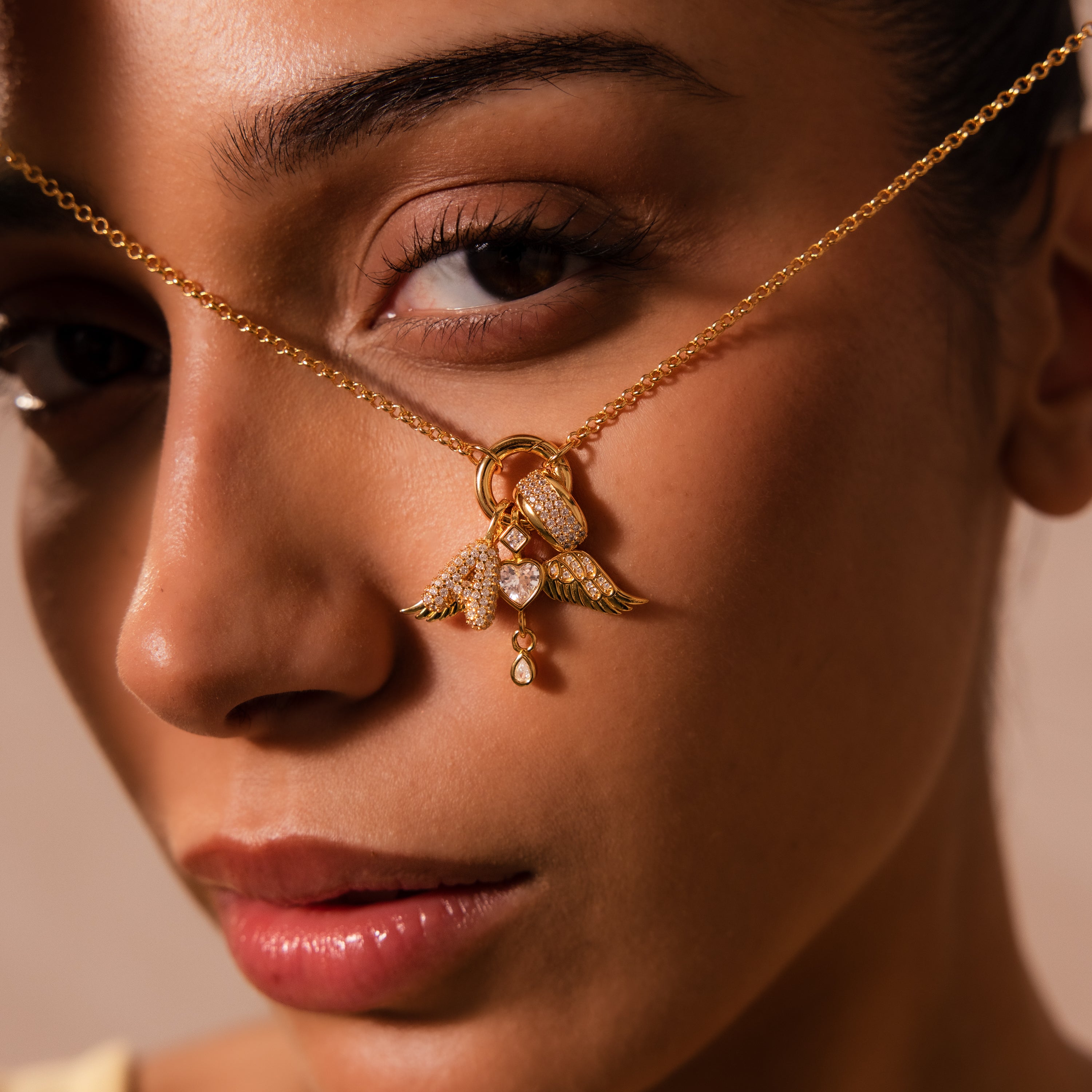 Woman holding a Pave Bubble Letter Charm necklace close to her face, accentuating her eye and lips.