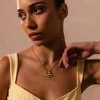 A woman in a yellow top showcases the Bold Pave Dome Charm in 18K Gold, its sparkling pendant adding a touch of elegance and charm to her look against a stylish beige background.