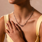 A woman wears the Rolo Circle Figaro Necklace in Silver with a yellow top, resting one hand on her chest.