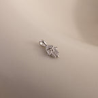 A close-up of the silver Evil Eye Hand Charm lying on a soft beige surface, showcasing its detailed stone-studded design.