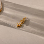 A close-up of a gold pendant featuring a sculpted hand holding an eight-pointed starburst charm set with an iridescent opal center