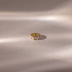 The Infinity Princess Alexandrite Charm, featuring shimmering princess-cut stones, displayed on a smooth, softly lit beige surface.