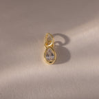 The Teardrop Diamond Charm features a gold teardrop design with a clear gemstone in a gold bezel setting, displayed on a light textured background with a soft shadow.