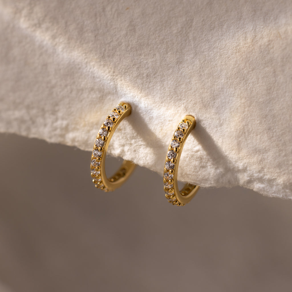 Diamond Clicker Huggies featuring small sparkling stones, shown on a textured cream background—ideal for adding stylish sparkle to your everyday look.