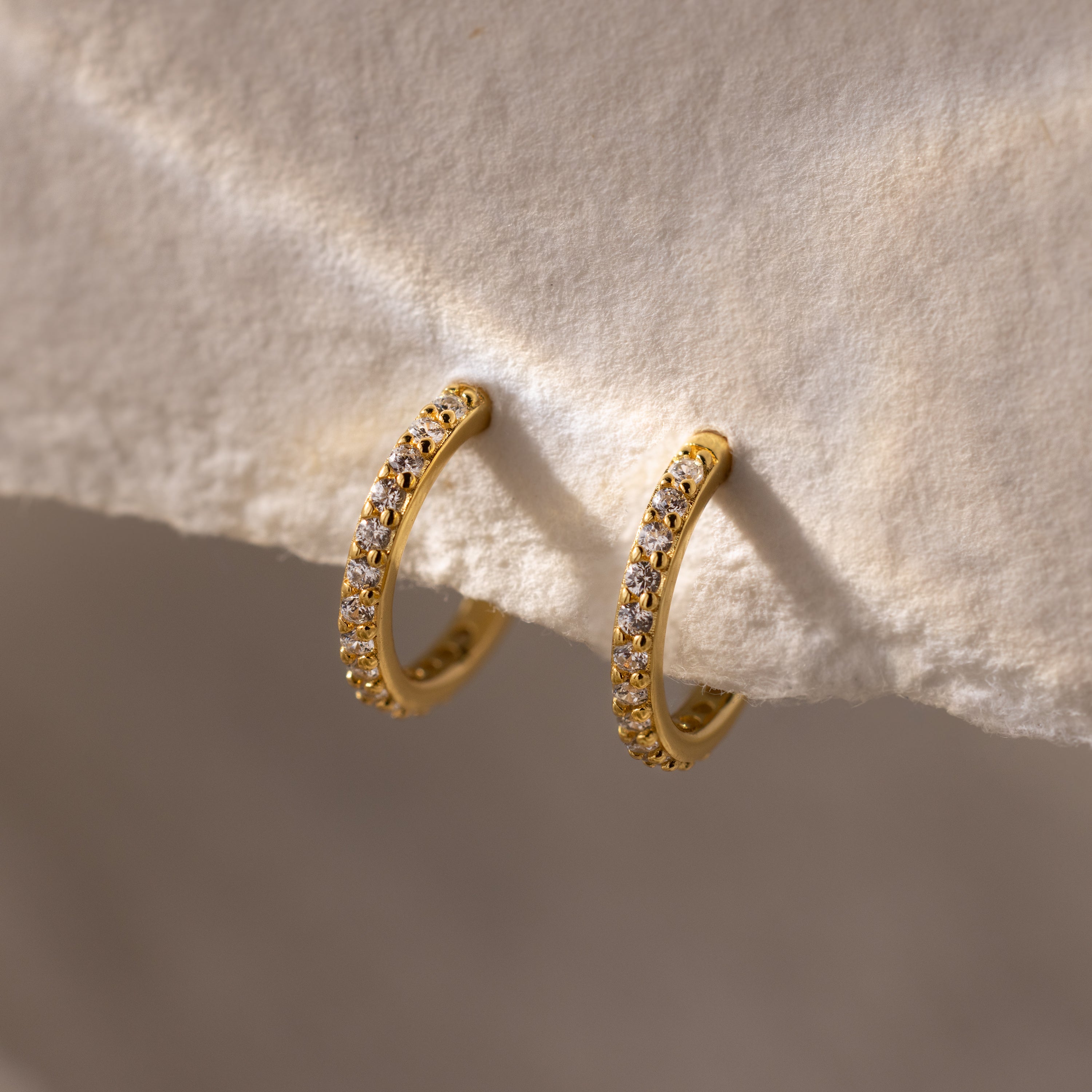 Diamond Clicker Huggies featuring small sparkling stones, shown on a textured cream background—ideal for adding stylish sparkle to your everyday look.