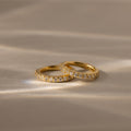 Two Diamond Clicker Huggies with small diamonds rest on a soft, beige surface in gentle light—perfect for pairing with your favorite everyday earrings.