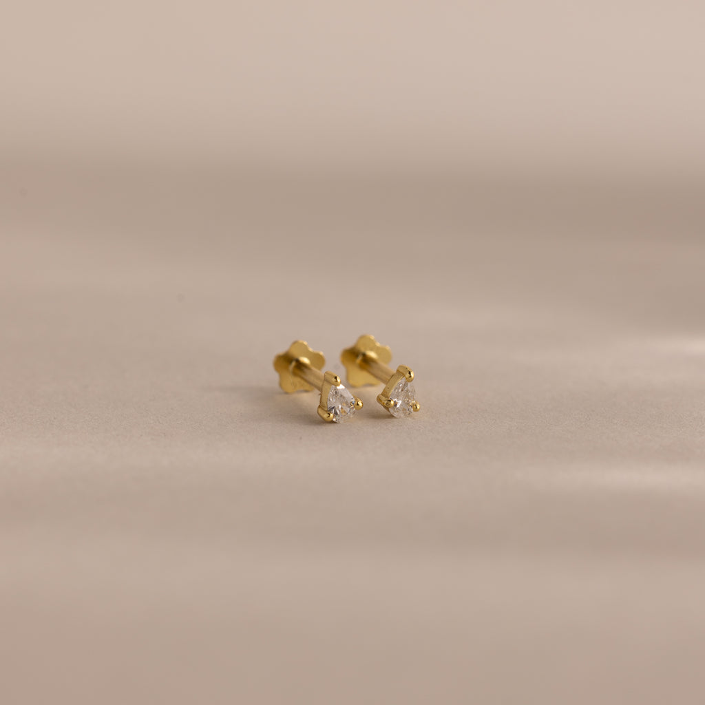 A pair of Teardrop Diamond Flatback Studs—small gold earrings set with clear gemstones—displayed on a neutral background.