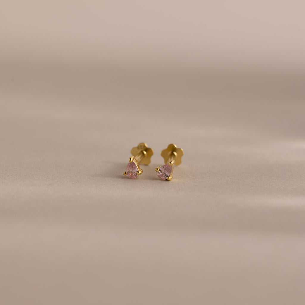 Teardrop Pink Tourmaline Flatback Studs—small gold studs with pink tourmaline gems—are perfect for a subtle touch of birthstone jewelry, displayed on a neutral background.