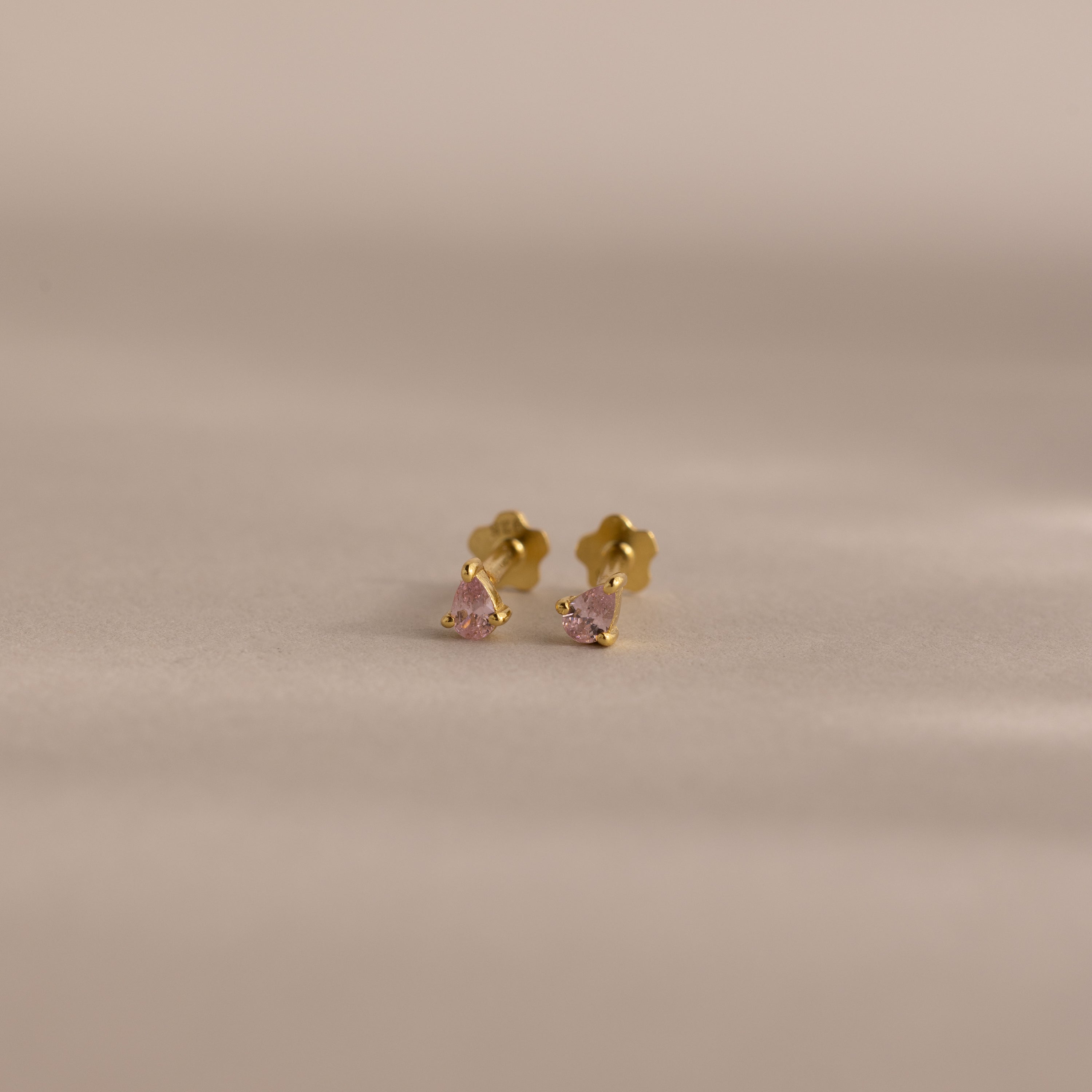 Teardrop Pink Tourmaline Flatback Studs—small gold studs with pink tourmaline gems—are perfect for a subtle touch of birthstone jewelry, displayed on a neutral background.
