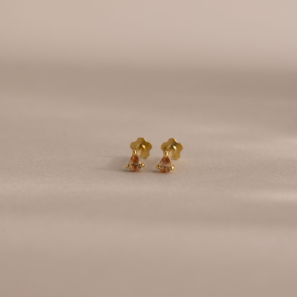Teardrop Topaz Flatback Studs with flower-shaped backs, shown on a softly lit neutral background—delicate birthstone earrings that make an ideal personalized gift.