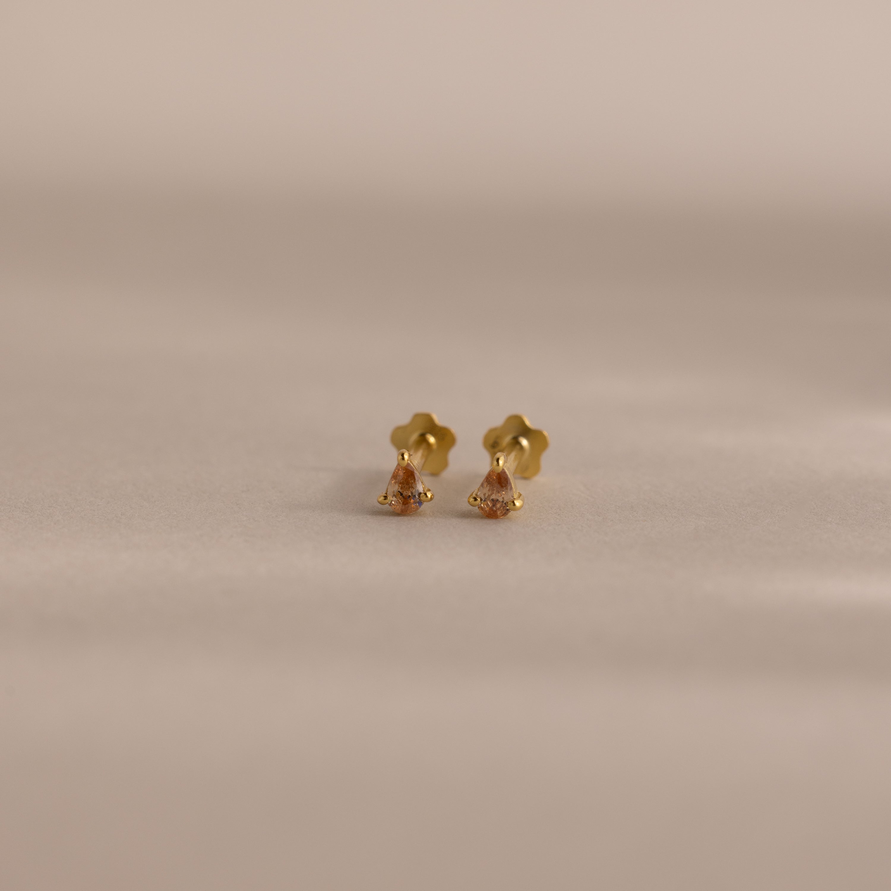 Teardrop Topaz Flatback Studs with flower-shaped backs, shown on a softly lit neutral background—delicate birthstone earrings that make an ideal personalized gift.