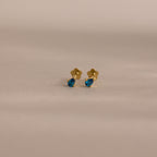 Teardrop Blue Zircon Flatback Studs: gold earrings featuring teardrop-shaped blue zircon gemstones, perfect for elegant birthstone jewelry lovers. Displayed on a neutral background.