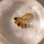 A gold keyring featuring five Teardrop Birthstone Charms in colorful bezels, elegantly displayed in a round, translucent dish.