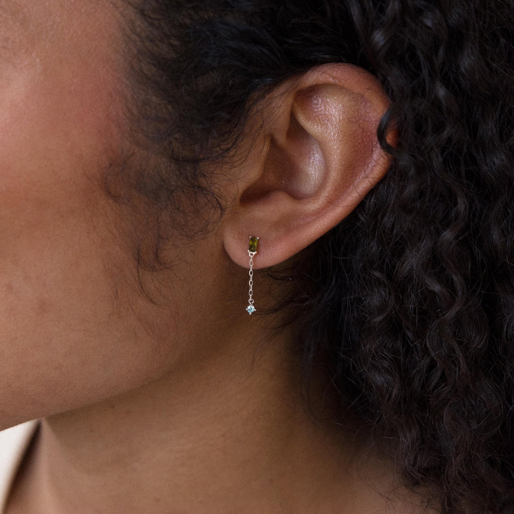A close-up of a woman's ear wearing Duo Birthstone Drop Studs, showcasing their elegant design.